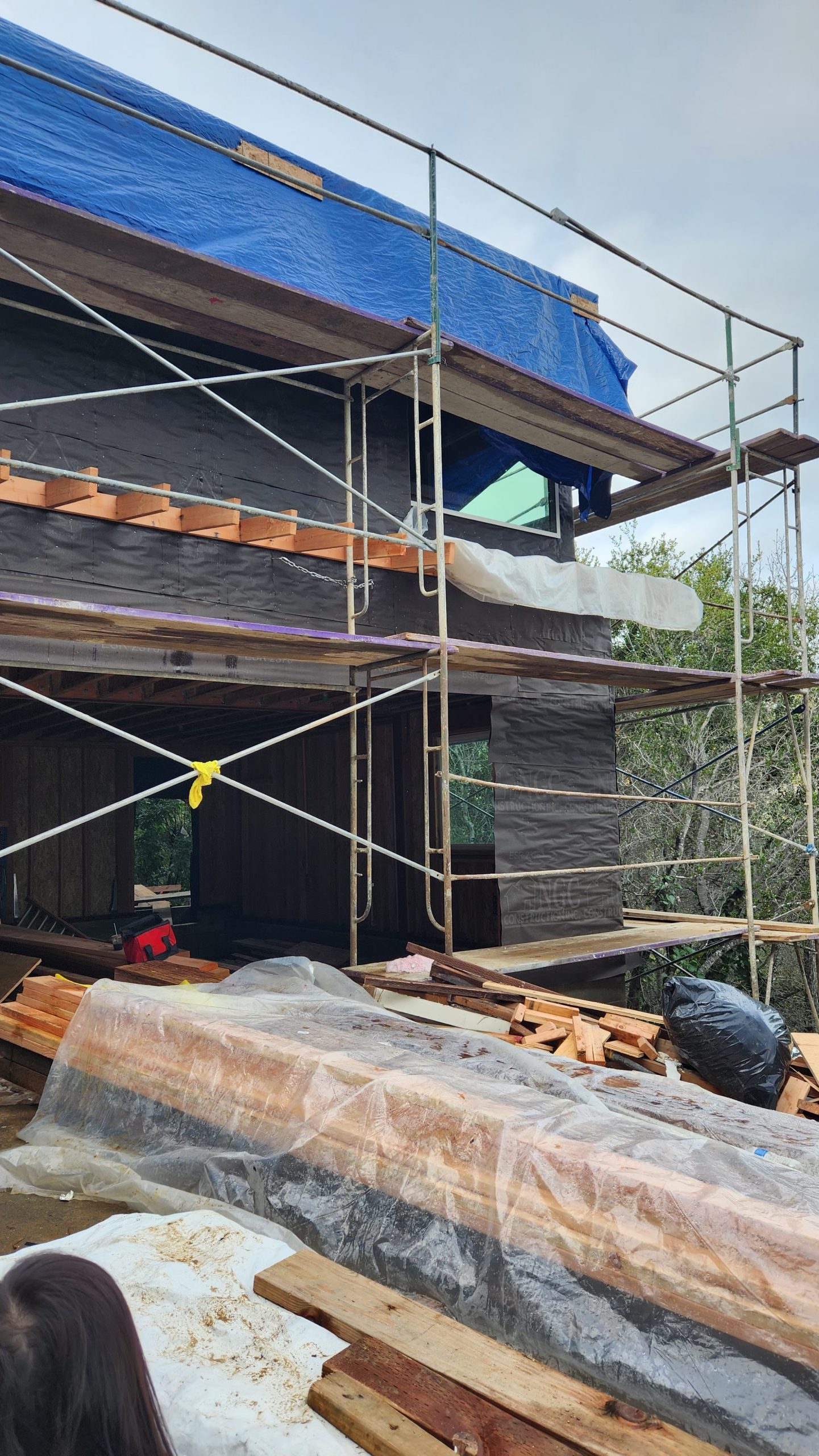 Framing and Sheathing in Progress – Exterior View with Scaffolding and Protective Tarp