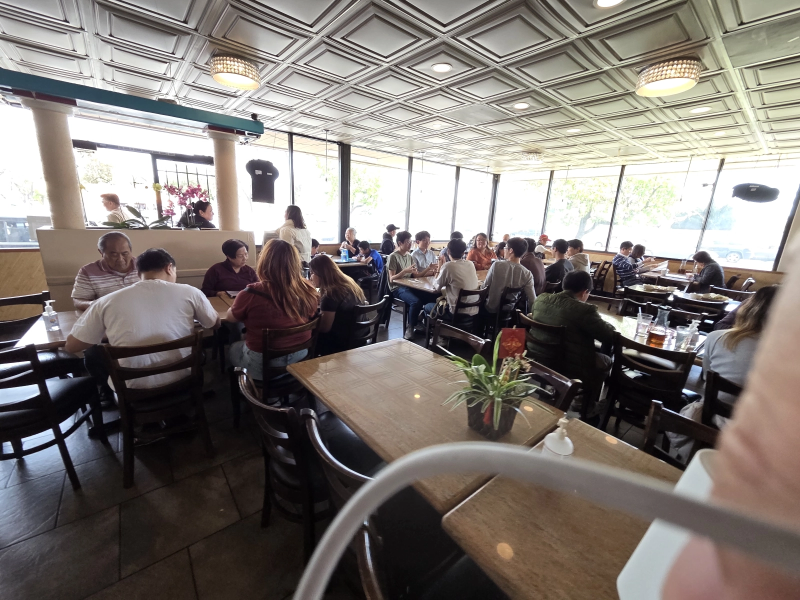 A crowded view of the restaurant, capturing the lively atmosphere at Com Tam Dat Thanh, with several groups of people enjoying their meals.